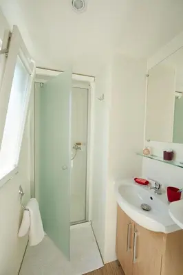 a white bathroom with a shower and a sink at Camping Victoria in Canet de Mar