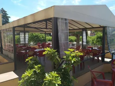 a restaurant with tables and chairs and a roof at Camping Victoria in Canet de Mar