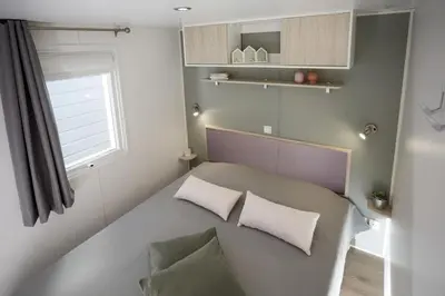 a small room with a bed with two pillows and a window at Camping Victoria in Canet de Mar