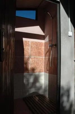 a shower in a bathroom with a shadow on the wall at Climbers Cabin in Marganell