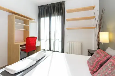 a bedroom with a white bed and a red chair at Playa Beach Barcelonastuff Apartments in Barcelona