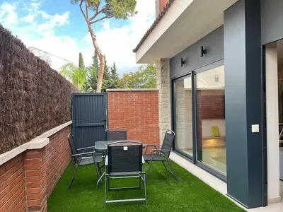 a patio with a table and chairs on the grass at Beautiful renovated studio in Castelldefels