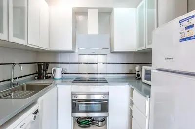 a white kitchen with white cabinets and a sink at AIGUADOLÇ APARTMENT in Sitges