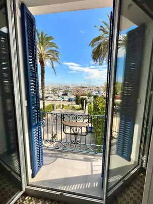 a window view of a balcony with a table and palm trees at Entire Flat First Beach line - Sea Views - Vilanova i Geltru in Vilanova i la Geltrú