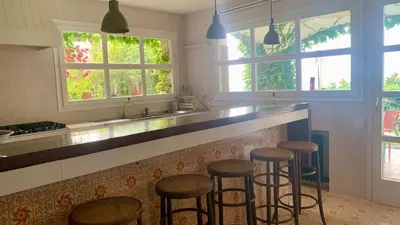 a kitchen with four bar stools at a counter at Villa Exclusiva 12 Personas con Piscina, Barbacoa y Vistas al Mar en Maresme Barcelona in Sant Vicenç de Montalt
