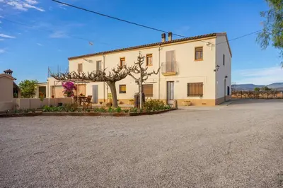 a large white building with a tree in front of it at Mas Prat in Pla del Panadés