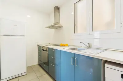 a kitchen with blue cabinets and a white refrigerator at 4151 - AB Sagrada Familia Views VII-II in Barcelona
