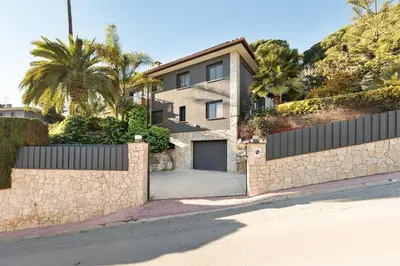 a house with a stone fence and a garage at Chez Pablo Barcelona in Cabrils