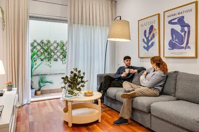a man and woman sitting on a couch in a living room at Acogedor apartamento en el corazón de Sant Antoni in Barcelona