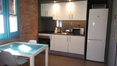 a kitchen with a table and a white refrigerator at Beach apartment with sea views in Barcelona