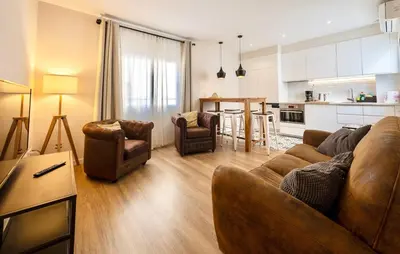 a living room with a couch and chairs and a kitchen at MadreMia - Wow Hub Barcelona in Hospitalet de Llobregat