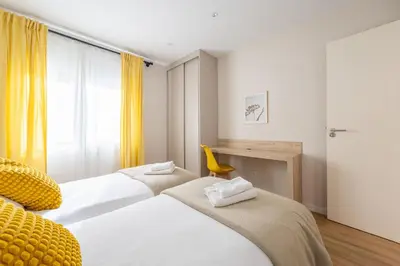 two beds in a room with yellow curtains at MadreMia - Wow Hub Barcelona in Hospitalet de Llobregat