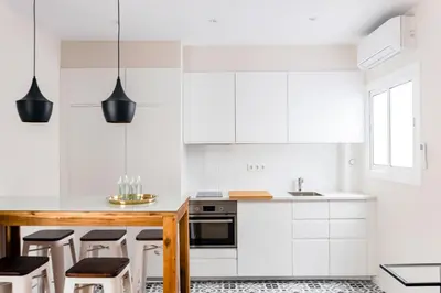 a kitchen with white cabinets and black stools at MadreMia - Wow Hub Barcelona in Hospitalet de Llobregat