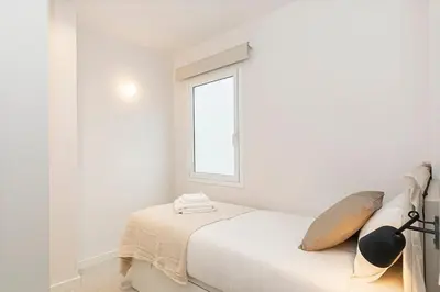 a white bedroom with a bed and a window at Penthouse with Terrace near Gran Via and Camp Nou in Barcelona