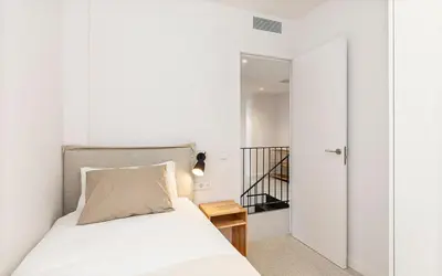 a small bedroom with a bed and a staircase at Penthouse with Terrace near Gran Via and Camp Nou in Barcelona
