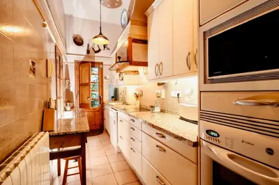 a large kitchen with white cabinets and a tv at HomeHolidaysRentals Suria - Costa Barcelona in San Pol de Mar