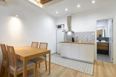 a kitchen and dining room with a wooden table and chairs at Ro Lively and bright apartment next to Blai st in Barcelona