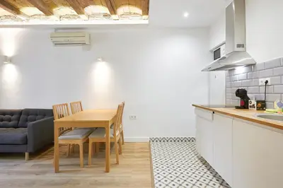 a kitchen and dining room with a table and a couch at Ro Lively and bright apartment next to Blai st in Barcelona