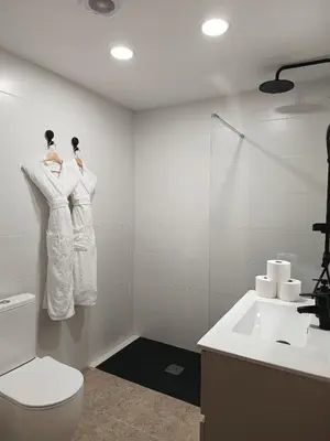 a bathroom with white robes hanging on a wall at CasaKech in Vilanova i la Geltrú