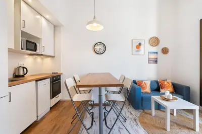 a kitchen and a living room with a table and a blue couch at Lodging Apartments Pere IV in Barcelona
