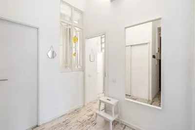 a white room with a mirror and a stool at Lodging Apartments Pere IV in Barcelona
