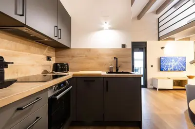 a kitchen with black appliances and wooden floors at Petit Luxe Del Vall in Terrassa