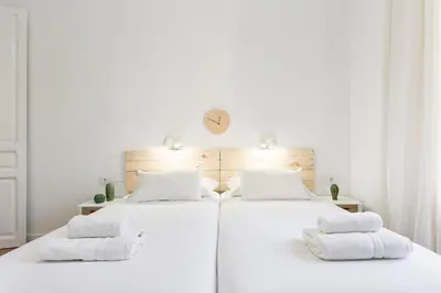 two beds in a white room with towels on them at Barcelona Central Park II in Barcelona