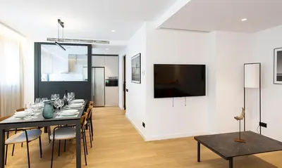 a dining room with a table and a television on a wall at Durlet Suites by Durlet Apartments in Barcelona