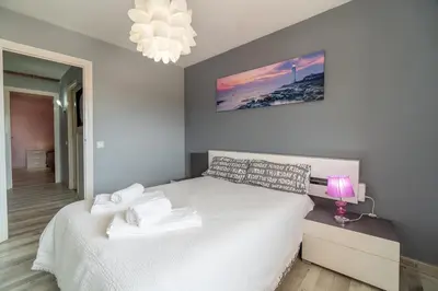 a bedroom with a white bed and a pink lamp at Side Sea Cunit sea views in Cunit