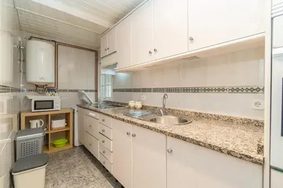 a kitchen with white cabinets and a sink at Side Sea Cunit sea views in Cunit