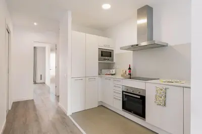 a kitchen with white cabinets and a stove top oven at Ola Living Arc de Triomf in Barcelona