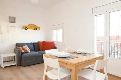 a living room with a table and a blue couch at Renovated apartment with sea view, VJ in Barcelona