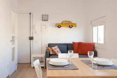 a living room with a table and a yellow car on the wall at Renovated apartment with sea view, VJ in Barcelona