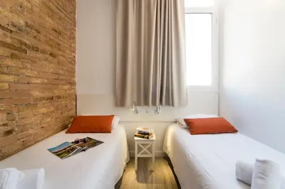 two beds in a room with a brick wall at Happy People Sagrada Familia Apartments in Barcelona