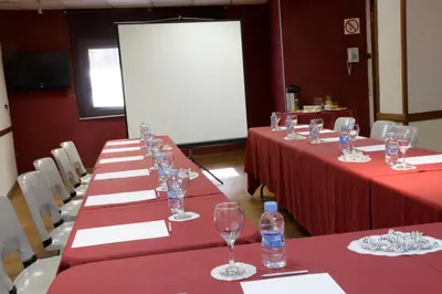 a row of tables with red table cloths and water bottles at Hotel Iris in Granollers