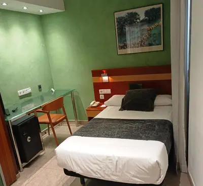 a hotel room with two beds and a desk at Hotel Iris in Granollers