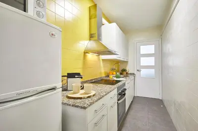 a small kitchen with white cabinets and yellow walls at BBarcelona Encants Flat in Barcelona