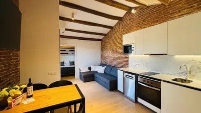 a kitchen and living room with a couch and a table at Céntrico ático by Prestigi in Terrassa