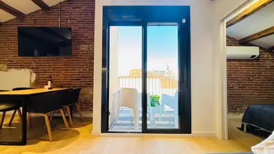 a dining room with glass doors leading to a balcony at Céntrico ático by Prestigi in Terrassa
