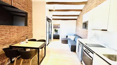 a kitchen and living room with a brick wall at Céntrico ático by Prestigi in Terrassa