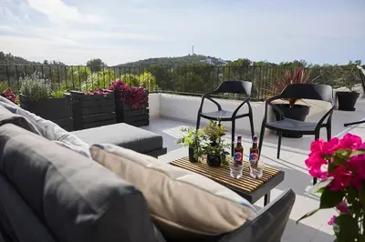 a patio with a couch and chairs and some flowers at Villa Sitges Casa Selva 7 minutos de Sitges en coche Diseño Comodidad Nueva Ideal para Vacaciones in Sant Pere de Ribes