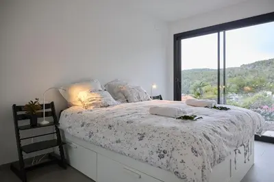 a bedroom with a bed with a large window at Villa Sitges Casa Selva 7 minutos de Sitges en coche Diseño Comodidad Nueva Ideal para Vacaciones in Sant Pere de Ribes