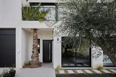 a front door of a house with a palm tree at Villa Sitges Casa Selva 7 minutos de Sitges en coche Diseño Comodidad Nueva Ideal para Vacaciones in Sant Pere de Ribes