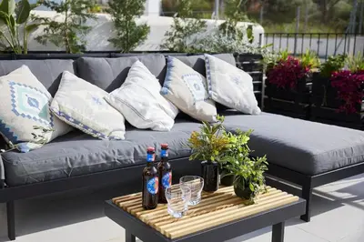 a couch with bottles and glasses on a table at Villa Sitges Casa Selva 7 minutos de Sitges en coche Diseño Comodidad Nueva Ideal para Vacaciones in Sant Pere de Ribes
