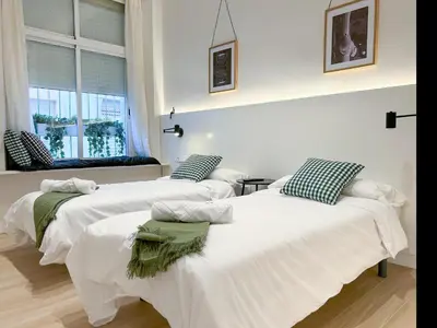 two white beds in a room with a window at Apartment Gaudi in Vilanova i la Geltrú