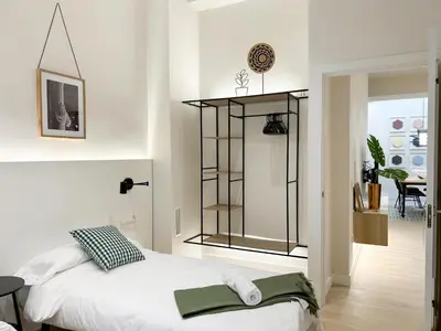 a white bedroom with a bed and a table at Apartment Gaudi in Vilanova i la Geltrú