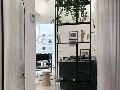 a room with a black book shelf with a chair at Apartment Gaudi in Vilanova i la Geltrú