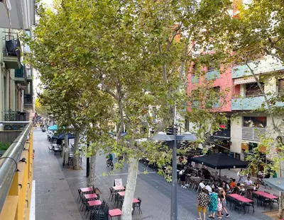 a view of a street with tables and chairs and a tree at Apartment Monet in Vilanova i la Geltrú