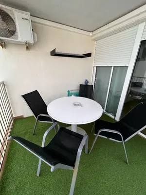 a white table and chairs in a room with green carpet at Apartment by the sea in Cubelles in Cubelles