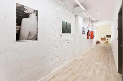 a hallway with white brick walls and photographs on the wall at Ant Hostel Barcelona in Barcelona